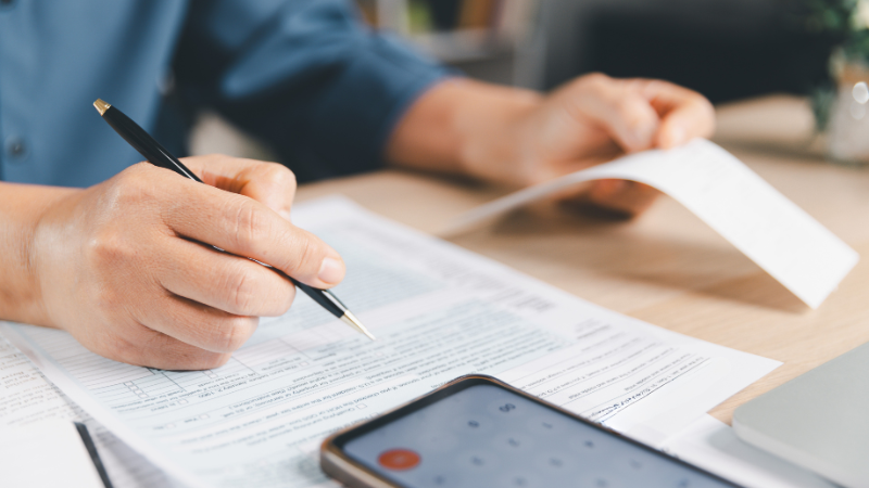 Close up of person's hands holding receipt and completing a form