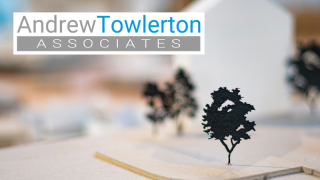 Close up of tree in model town with other trees, a house and other elements blurred in the background